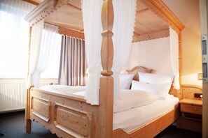 A wooden four-poster bed with white bedding, a wooden nightstand, and a window with curtains. - Hotel Lonac (Duisburg)