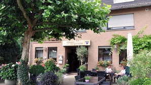 A hotel entrance with a sign, outdoor seating, and potted plants.
