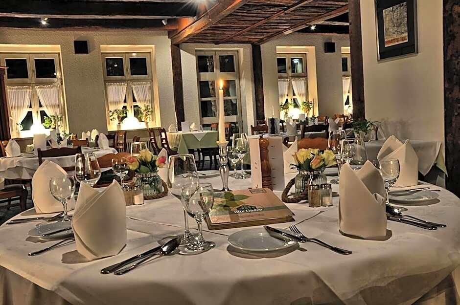 A dining area with round tables set for a meal, featuring white tablecloths, glassware, and floral centerpieces.
