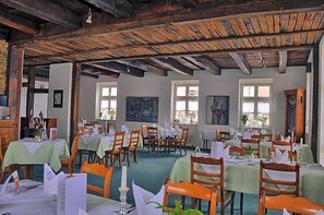 Een restaurant met houten balken, gedekte tafels en kunst aan de muren.