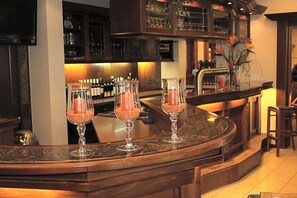 A bar area with a curved countertop, bar stools, and a variety of bottles and glasses.