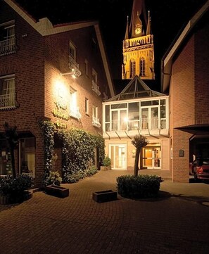 A hotel with a brick facade, a clock tower, and a well-lit entrance.