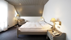 A hotel room with a bed, a chair, a desk with a phone, and a lamp. - Flair-goldener Stern (Ascheberg)