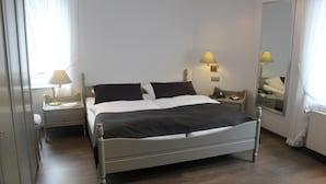 A hotel room with a bed, bedside tables, a mirror, and a window with curtains. - Flair-goldener Stern (Ascheberg)