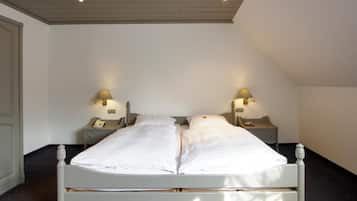 A double bed with two bedside tables, each with a lamp, in a room with a sloped ceiling and a black floor.