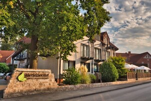 Un hotel con fachada de piedra, un balcón y un cartel que dice 'Merfelder Hof Hotel & Restaurant'.