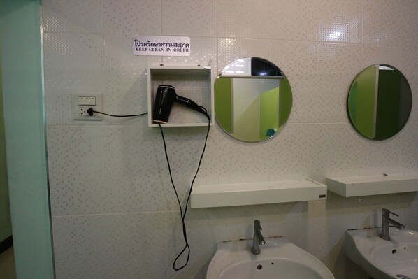 A bathroom with two sinks, a hairdryer, and a sign instructing to keep the area clean.