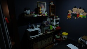Une cuisine équipée d’un four à micro-ondes, d’un réfrigérateur et de divers ustensiles de cuisine rangés sur des étagères.
