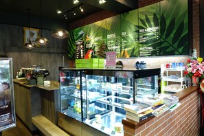 A coffee shop interior with a menu board, a display case with books, and a counter with a coffee machine.