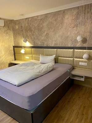 Une chambre à coucher moderne avec un lit, des tables de chevet et des lampes suspendues.