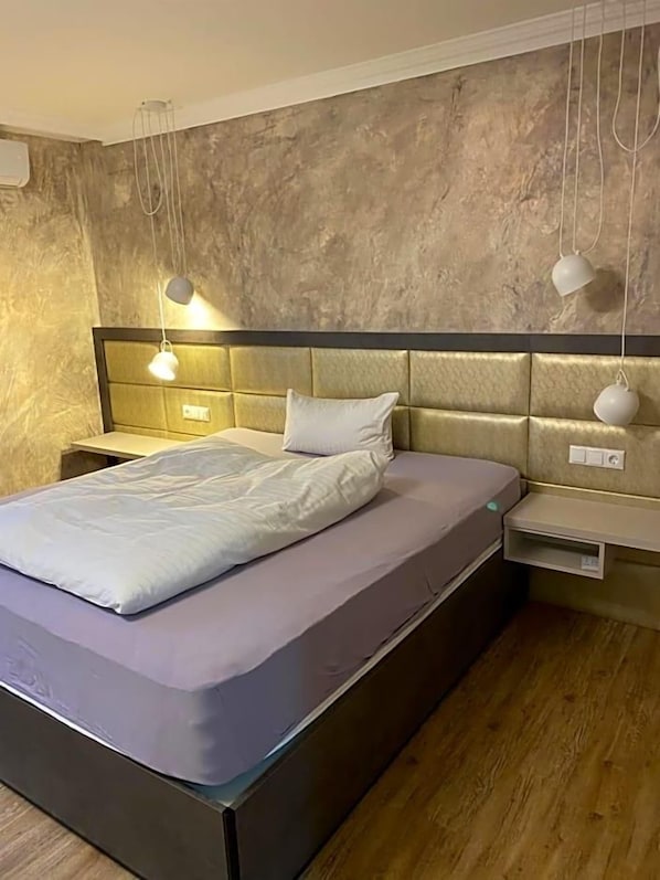 A modern bedroom with a bed, bedside tables, and pendant lights.