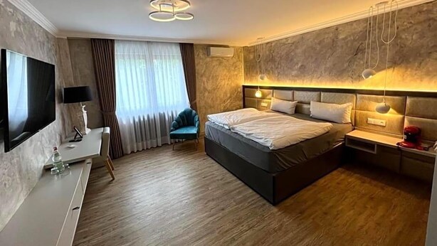 Una habitació d'hotel moderna amb un llit gran, televisió de pantalla plana, escriptori i zona de seients còmoda.