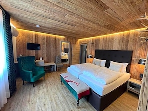 Une chambre à coucher aux murs lambrissés, avec un lit, une chaise, un bureau et un miroir.