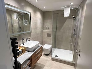 Un bagno moderno con cabina doccia in vetro, lavandino bianco e WC.