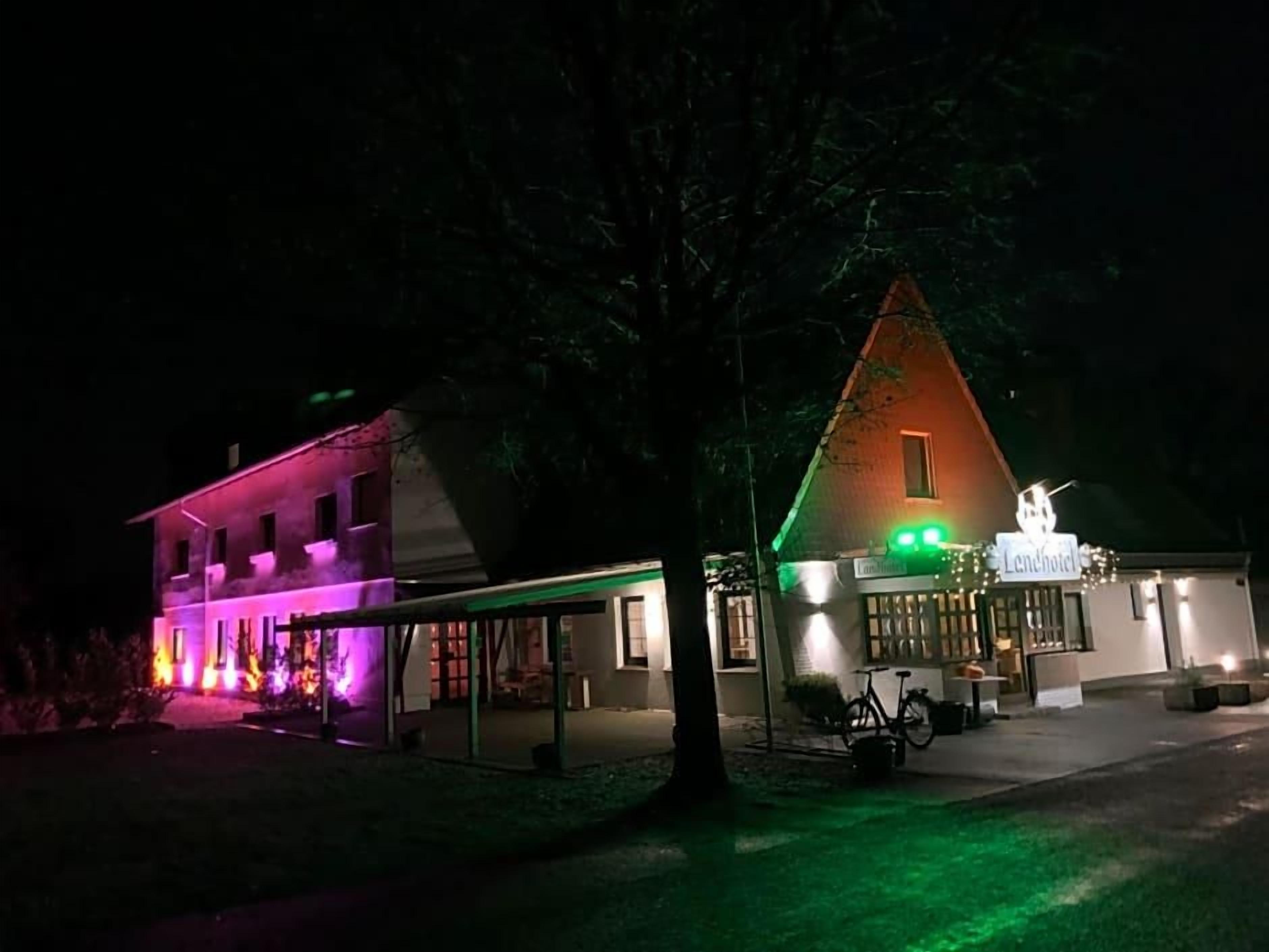 A hotel with a prominent sign, a covered outdoor seating area, and a bicycle parked outside.