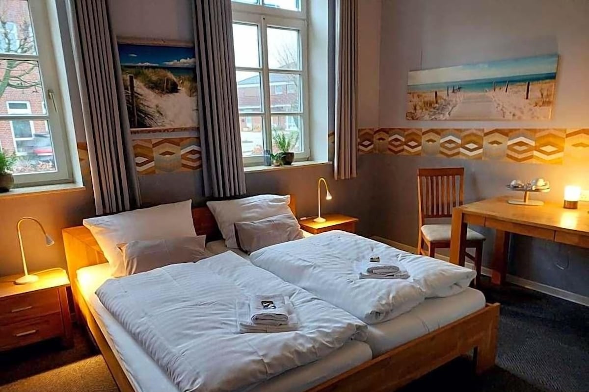 Une chambre d’hôtel avec un lit double, un bureau, une chaise et une fenêtre avec des rideaux.