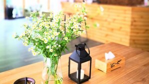 Ein Holztisch mit Blumen in einer Vase, einem Kerzenständer und einer Laterne.
