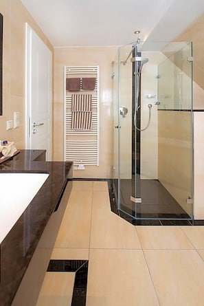 A modern bathroom with a glass-enclosed shower, a white sink, and a towel rack. - Birkenfelder Hof (Birkenfeld)