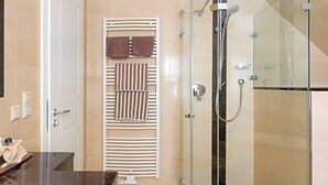 A modern bathroom with a glass-enclosed shower, a white sink, and a towel rack. - Birkenfelder Hof (Birkenfeld)