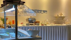 A buffet setup with a variety of food items and a coffee station.