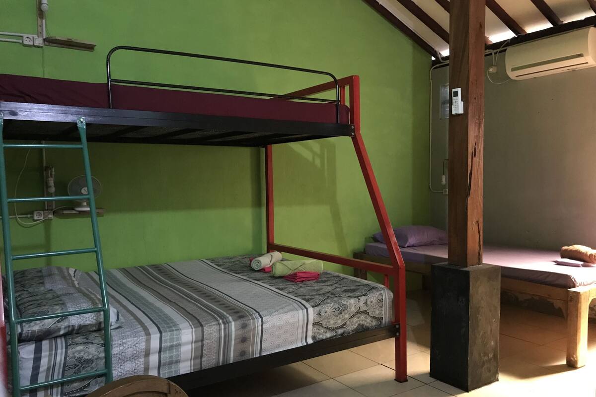 Een stapelbed met een ladder, een klein tafeltje en een kussen op het onderste bed.