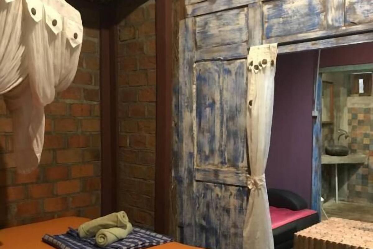 Een kamer met een bed, een tafeltje en een gordijn.