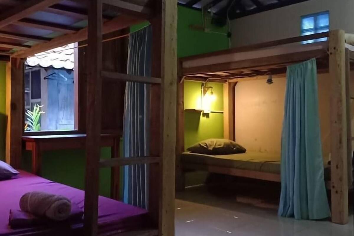 Een kamer met twee stapelbedden, een klein raam en een groene wand.