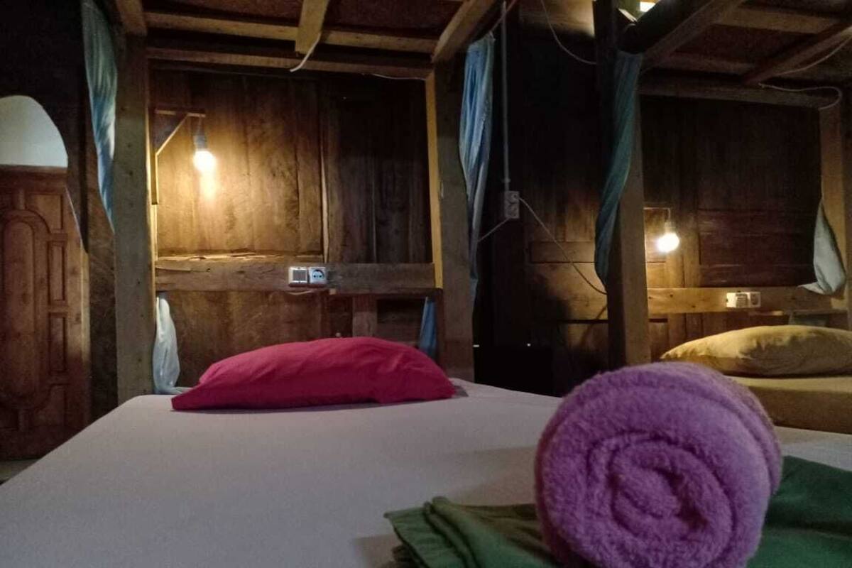 Een houten kamer met een bed, een nachtkastje en een lamp.
