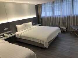 Een moderne hotelkamer met een groot bed, nachtkastjes, een telefoon en een stoel.