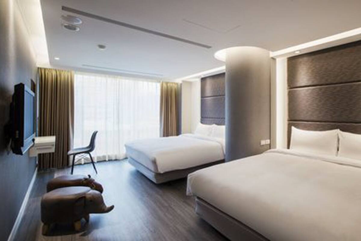 A hotel room with a large bed, a smaller bed, a desk, and a chair.