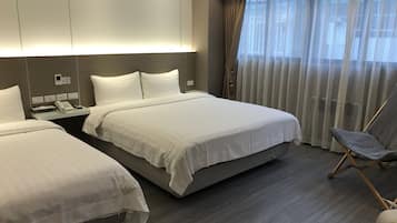 A hotel room with two beds, a desk with a phone, and a chair.