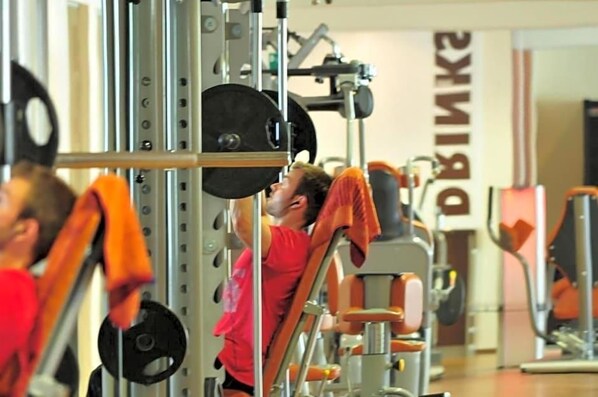 Une salle de sport équipée de matériel de musculation et dotée d’un miroir au mur.