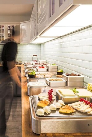 A buffet setup with various food items and a person serving. - Hotel Santo (Karlsruhe)
