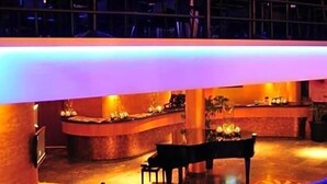 A modern hotel lobby with a curved reception desk, seating area, and a staircase leading to an upper level. - Hotel Santo (Karlsruhe)