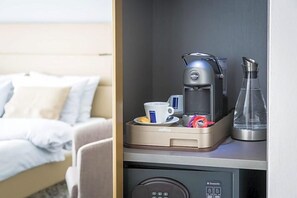 A hotel room with a bed, a coffee machine, a cup, and a glass on a counter. - Hotel Santo (Karlsruhe)