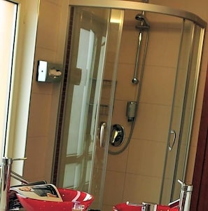 A glass-enclosed shower stall with a handheld showerhead and a control panel. - Hotel Santo (Karlsruhe)