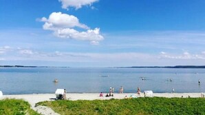 A beach with people swimming and relaxing on the sand. - Strandhotel Lodge am Meer (Gluecksburg)