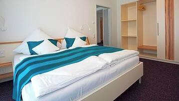 A hotel room with a bed, a wardrobe, and a shower area.
