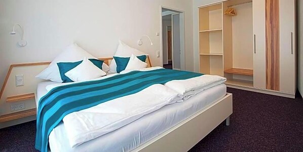 Una habitación de hotel con cama, mesitas de noche, armario y baño.