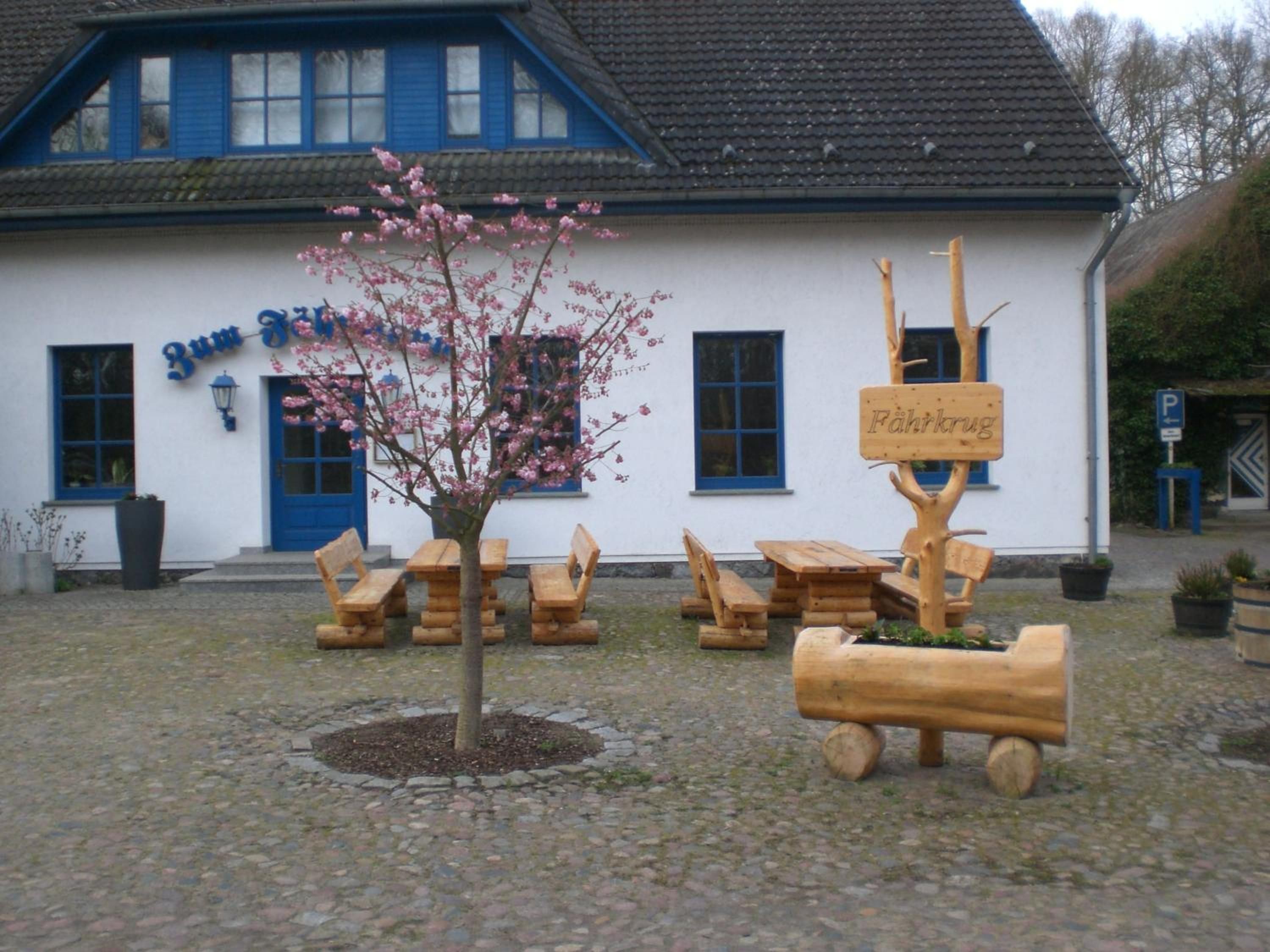 A building with a sign reading 'Zum Fisch' and a wooden signpost with 'Fahrkug' written on it.