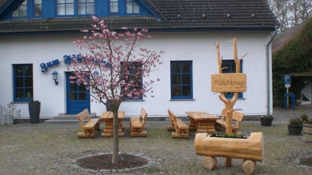 A building with a sign reading 'Zum Fisch' and a wooden signpost with 'Fahrkug' written on it.