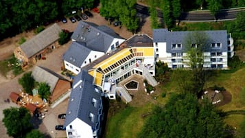 Ein mehrstöckiges Gebäude mit einem zentralen Innenhof, umgeben von Parkplätzen und Grünflächen.
