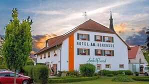 Un edificio blanco con el letrero 'HOTEL AM UCKERSSEE' y 'Schilfland' escrito en él.