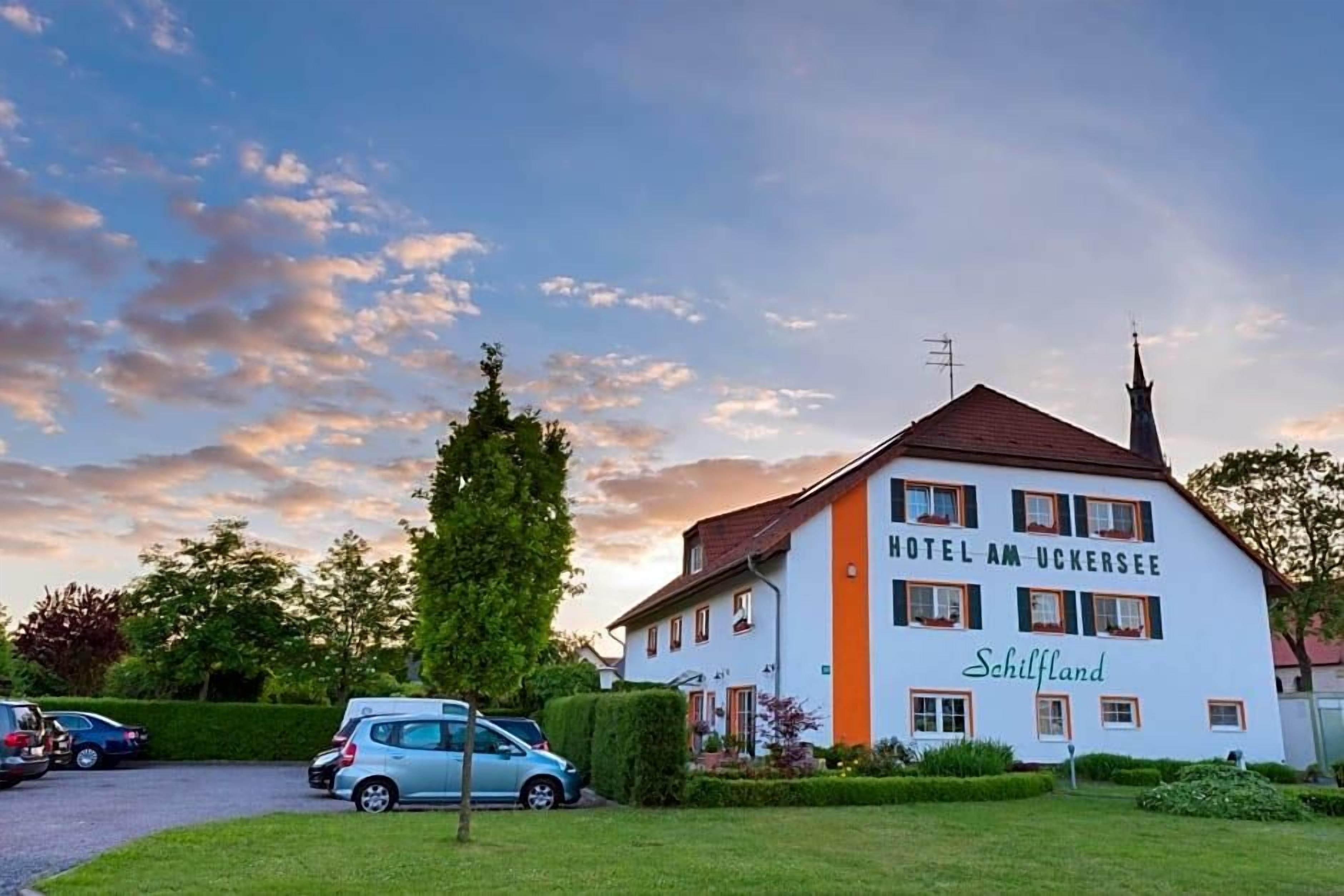 A hotel building with a sign reading 'HOTEL AM UCKERSEE' and 'Schilfland' on the side.