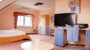 Ein Schlafzimmer mit Bett, Schreibtisch, Fernseher und Stuhl.
