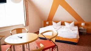 Habitación de hotel con una cama, dos mesitas de noche, una mesa redonda y sillas.