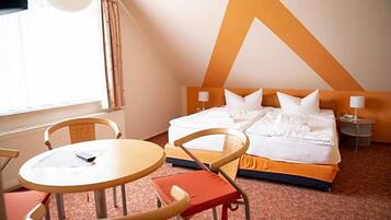 Ein Hotelzimmer mit einem Bett, zwei Nachttischen, einem runden Tisch und Stühlen.