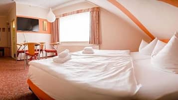 Ein Hotelzimmer mit Bett, Schreibtisch, Stuhl, Fernseher und Fenster.