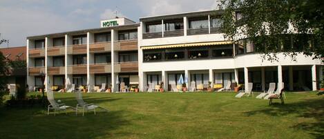 Un hotel de dos pisos, con área de estar al aire libre con sillones y un césped bien cuidado.