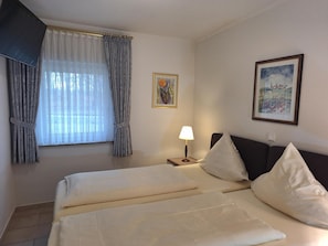 A hotel room with a bed, a nightstand, a lamp, and two paintings on the wall.